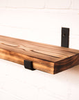 Flamed wooden radiator shelf made from scaffolding boards with hanging brackets.