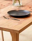 Antique Wooden dining table with black plates and fork on a wooden floor.