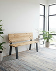 Wooden bench in a modern room with large windows and plants.