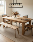 Dining room with wooden table, chairs, and bench on a rug.