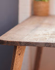 Close-up of a reclaimed scaffold board corner desk top with visible wood grain and slightly rounded edges.