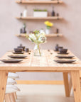 Rustic Dining table set with plates and a vase in a room with shelves in the background