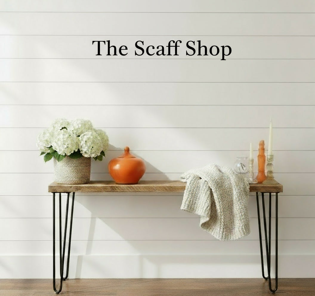 Wooden bench with decorative items against a white wooden panel wall, featuring 'The Scaff Shop' text.