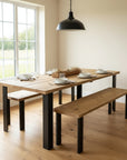 Scaffold Dining table with benches in a bright room with large windows leaving a modern feel.