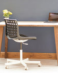 Wooden desk with a chair and laptop against a gray wall