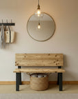 Wooden bench in a hallway with a mirror, light fixture, and basket, 