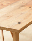 Close-up of a wooden table with visible grain and texture. No oil finish