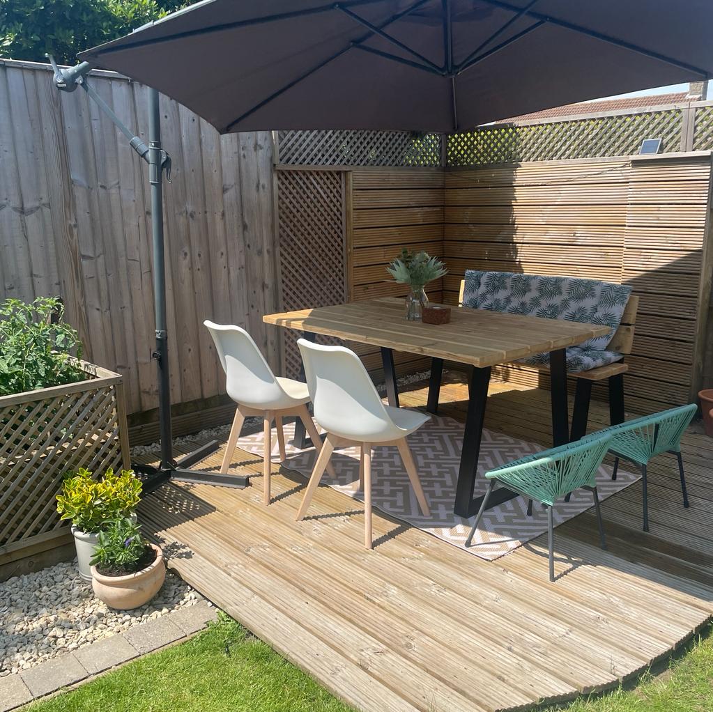 Outdoor timber table with black legs on a wooden decking area