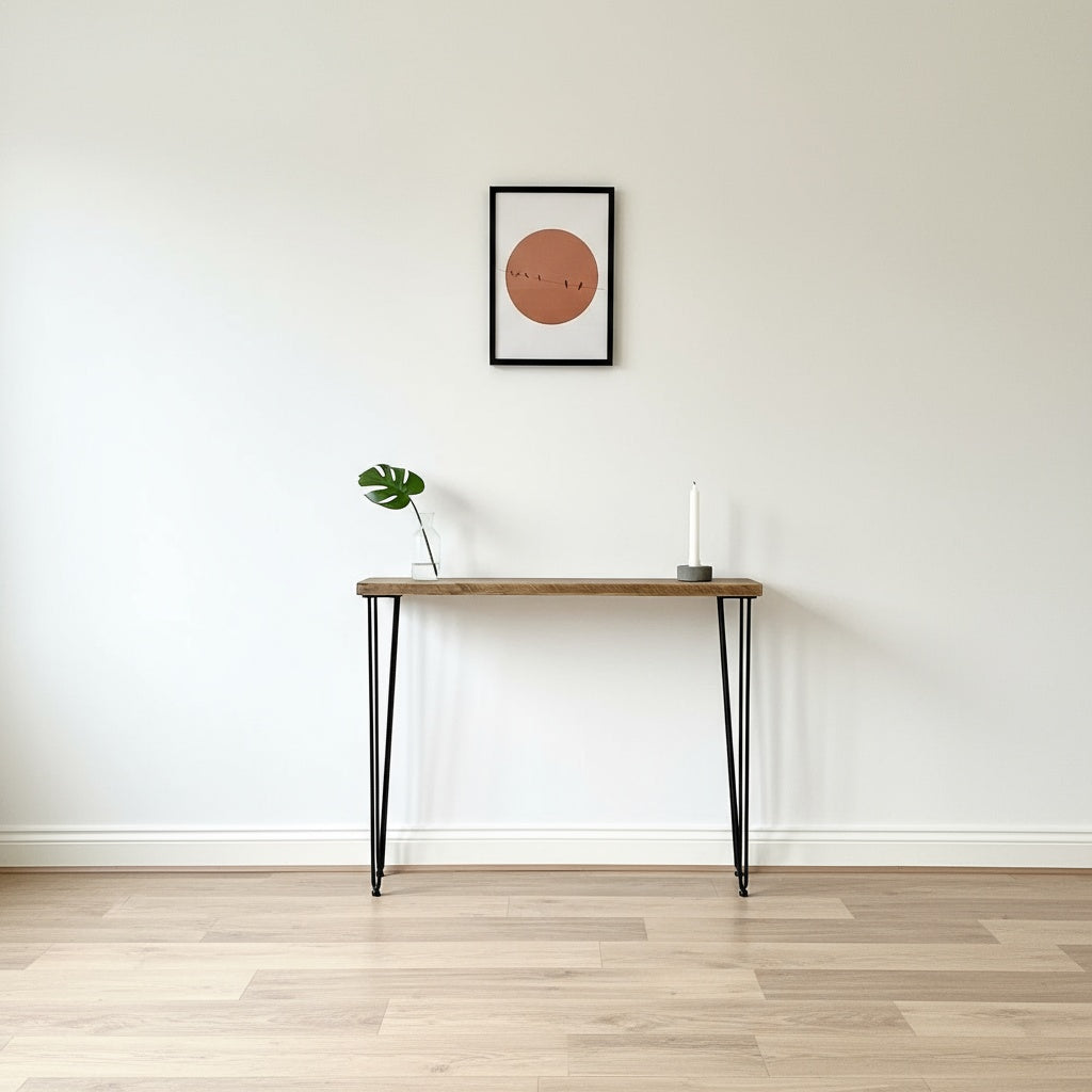 Wooden table with black legs against a white wall with a framed picture.